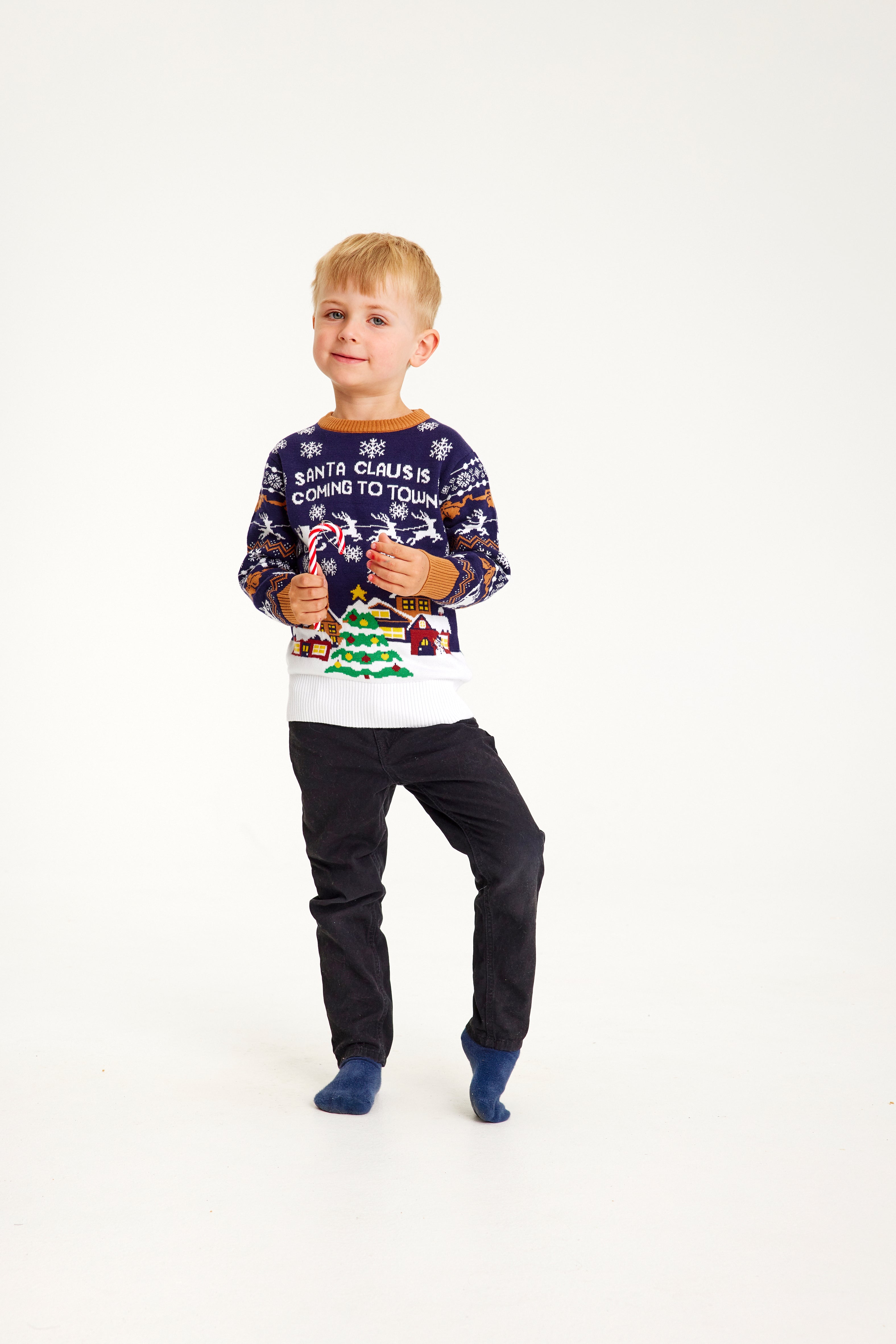 Et barn iført en blå julesweater med et juletræ på.